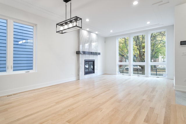 unfurnished living room with a tiled fireplace and light hardwood / wood-style floors