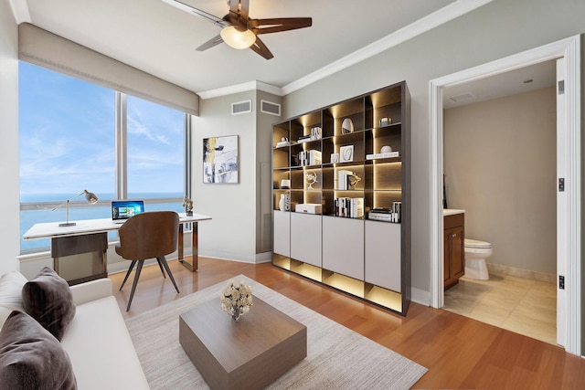 living room featuring light wood-type flooring, a water view, ceiling fan, and crown molding