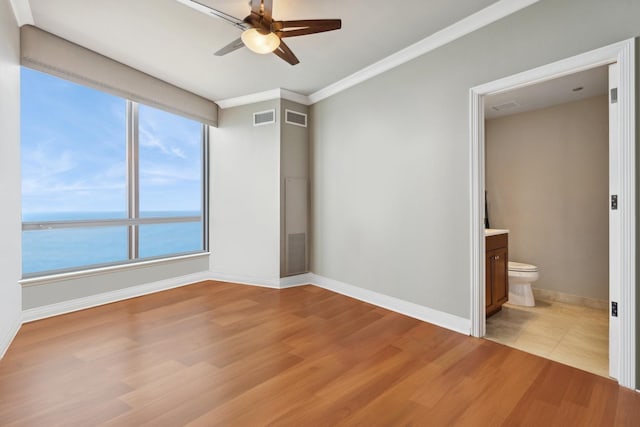 empty room featuring crown molding, a water view, light hardwood / wood-style floors, and ceiling fan