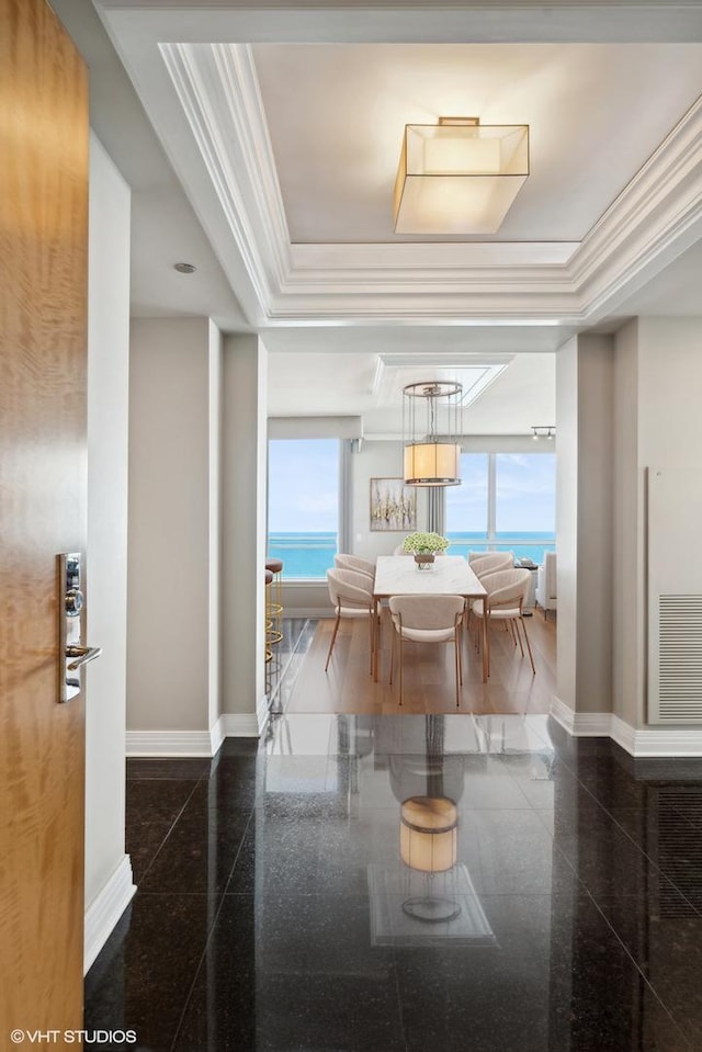 dining room with a water view, a raised ceiling, and crown molding