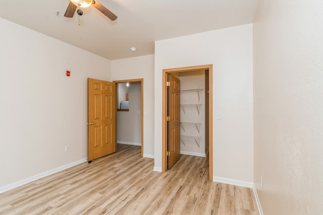 unfurnished bedroom featuring a walk in closet, ceiling fan, a closet, and light hardwood / wood-style floors