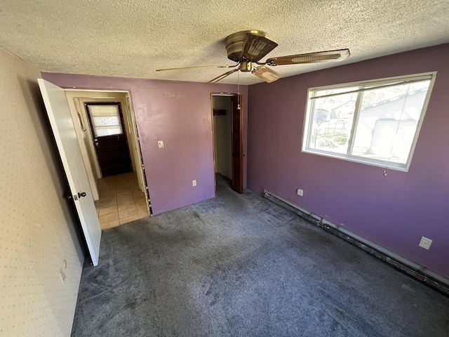 unfurnished bedroom with ceiling fan, carpet floors, and a textured ceiling