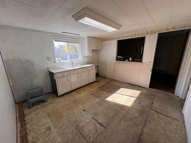 kitchen with decorative backsplash, white cabinetry, and sink