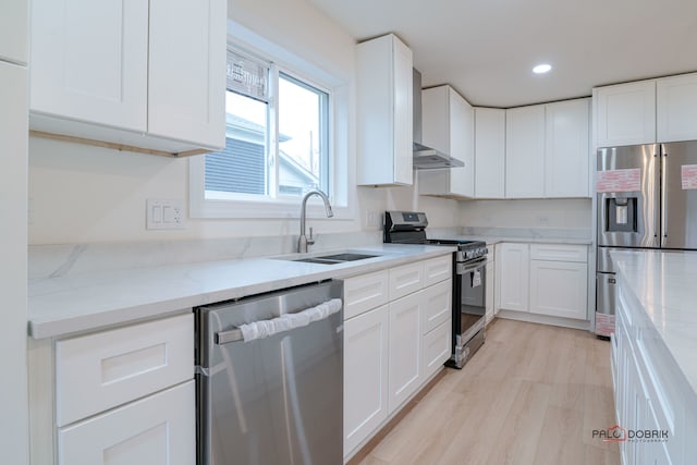 kitchen with white cabinetry, light wood-type flooring, light stone counters, and appliances with stainless steel finishes