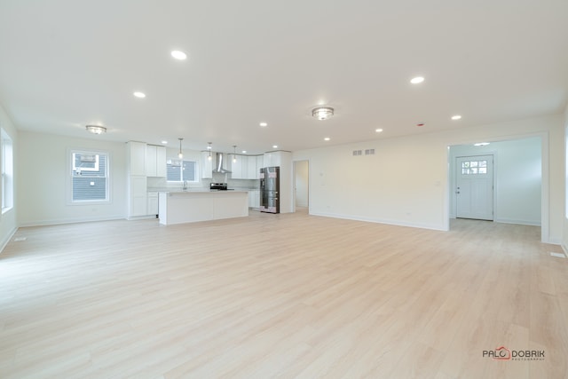 unfurnished living room featuring light wood-type flooring and sink