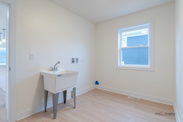 washroom featuring hookup for a washing machine and light hardwood / wood-style flooring