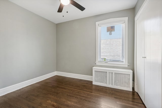 unfurnished room featuring radiator heating unit, ceiling fan, and dark hardwood / wood-style floors