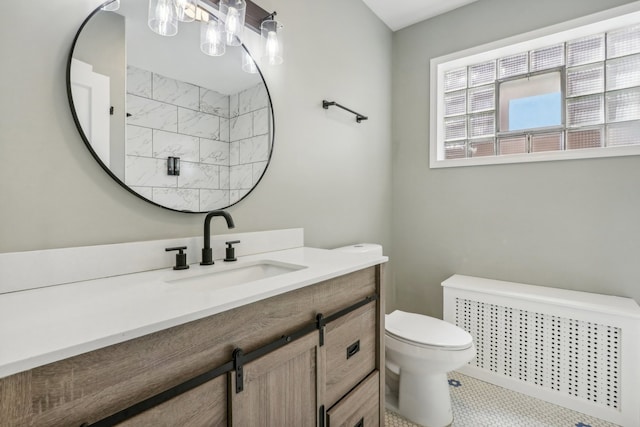 bathroom featuring tile patterned flooring, radiator heating unit, vanity, and toilet