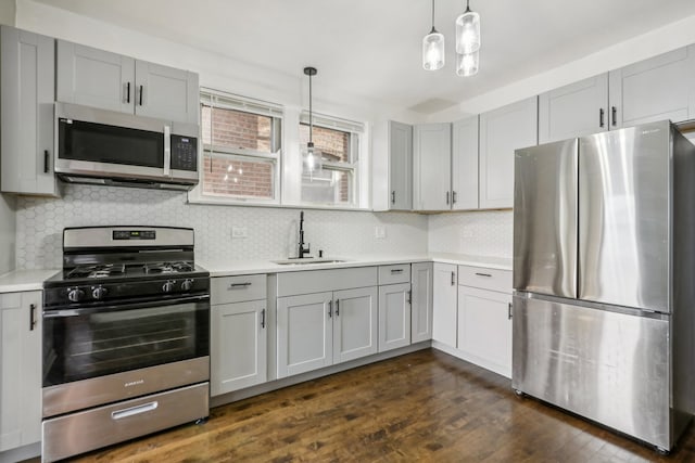 kitchen featuring dark hardwood / wood-style flooring, sink, hanging light fixtures, and appliances with stainless steel finishes