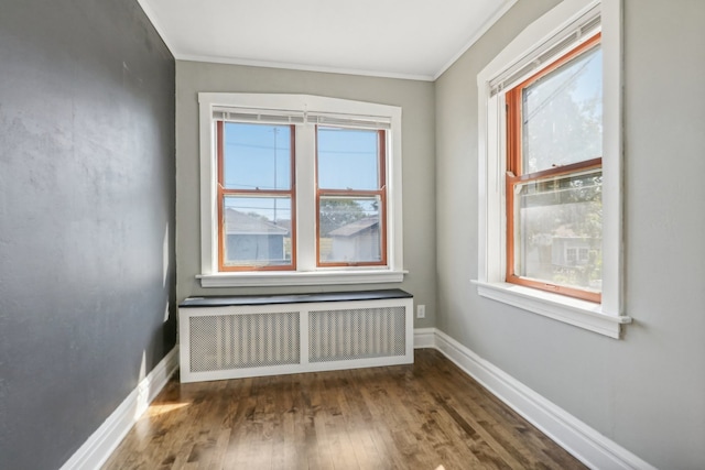 empty room with radiator heating unit, ornamental molding, and dark wood-type flooring