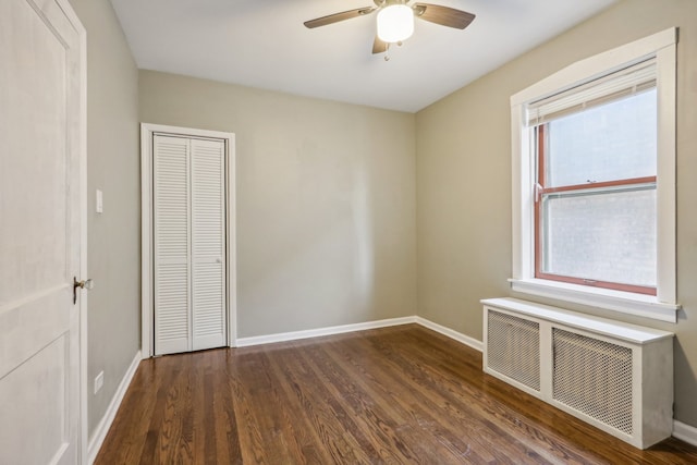 unfurnished bedroom featuring a closet, radiator, dark wood-type flooring, and ceiling fan