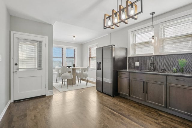 kitchen with stainless steel fridge, backsplash, a healthy amount of sunlight, and pendant lighting