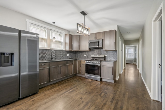 kitchen featuring sink, pendant lighting, decorative backsplash, dark wood-type flooring, and stainless steel appliances