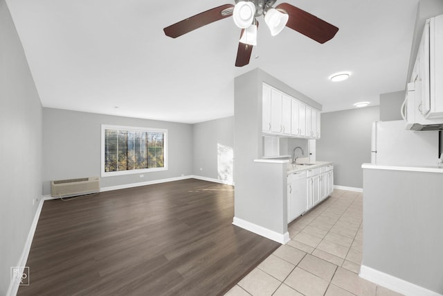 kitchen featuring ceiling fan, a wall mounted AC, white appliances, white cabinets, and light wood-type flooring