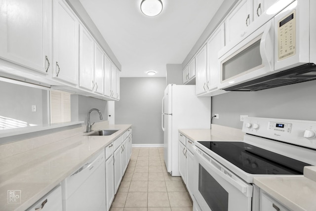 kitchen with white appliances, white cabinets, sink, light stone countertops, and light tile patterned floors