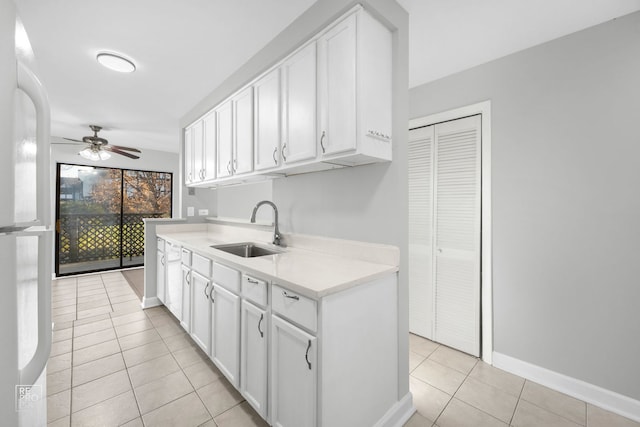 kitchen with ceiling fan, sink, light tile patterned floors, white fridge, and white cabinetry