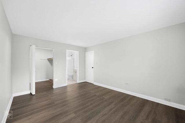 unfurnished bedroom featuring ensuite bathroom, a closet, a spacious closet, and dark hardwood / wood-style floors