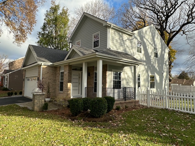 view of front of property with covered porch, a garage, and a front lawn