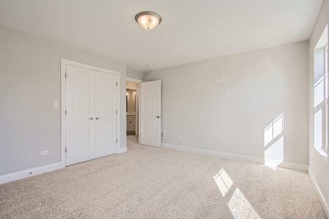 unfurnished bedroom with light carpet and a closet