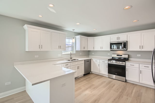 kitchen with sink, stainless steel appliances, kitchen peninsula, light hardwood / wood-style floors, and white cabinets