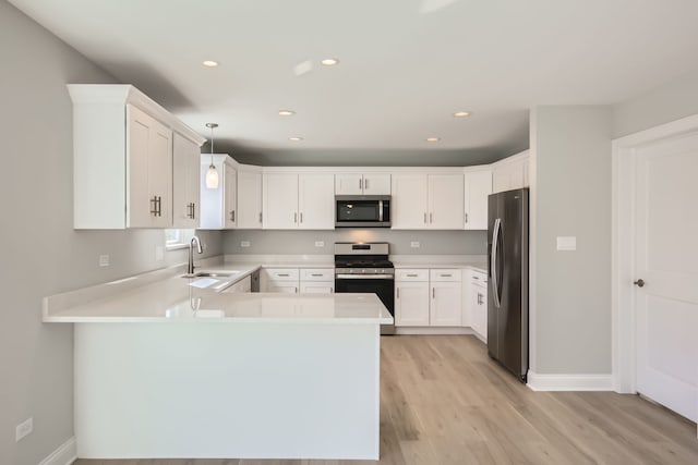 kitchen with sink, stainless steel appliances, decorative light fixtures, white cabinets, and light wood-type flooring