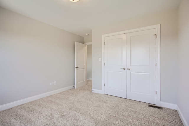 unfurnished bedroom with a closet and light colored carpet