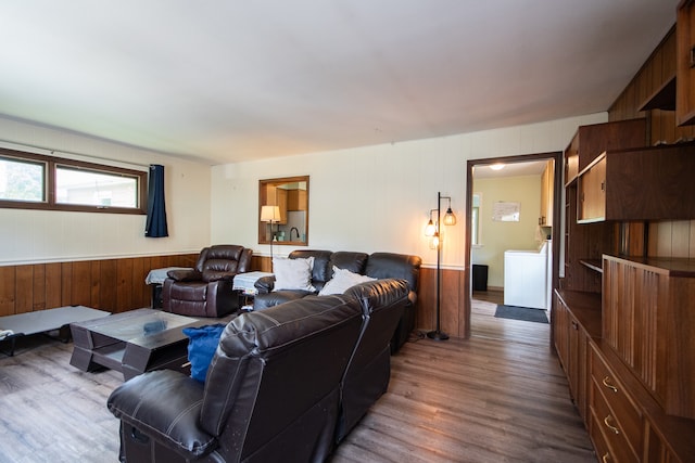 living room with washer / dryer, hardwood / wood-style flooring, and wood walls