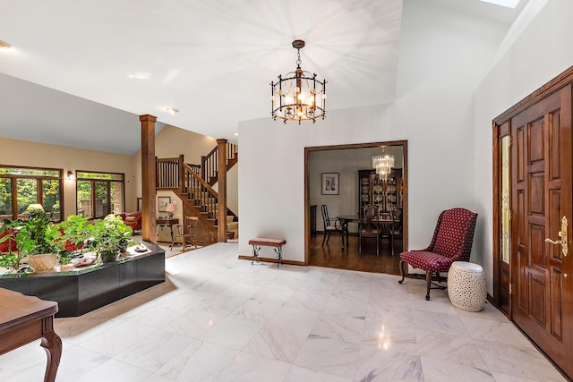 entrance foyer with a towering ceiling, a chandelier, and ornate columns