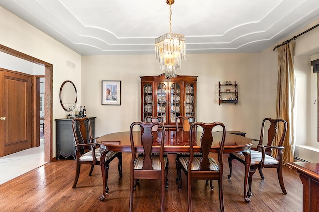 dining room featuring wood-type flooring and an inviting chandelier