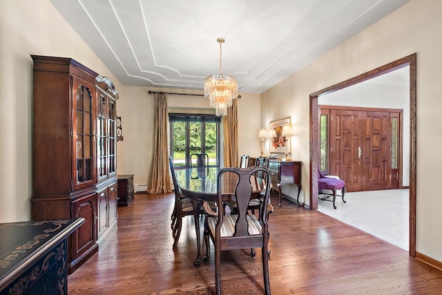 dining space with an inviting chandelier, a baseboard heating unit, dark wood-type flooring, and a raised ceiling