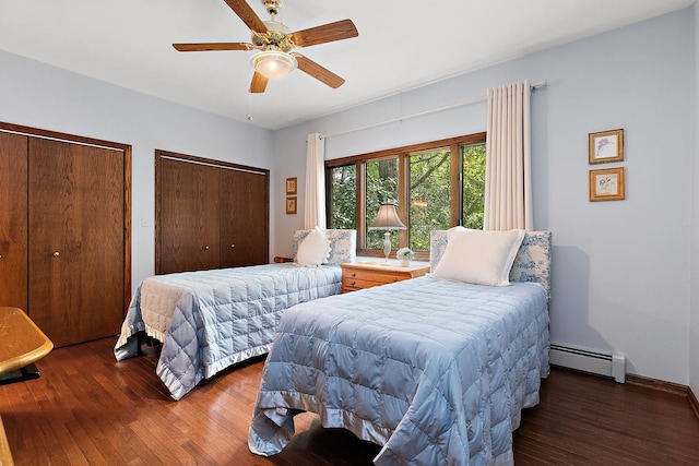 bedroom featuring ceiling fan, two closets, dark hardwood / wood-style floors, and a baseboard heating unit