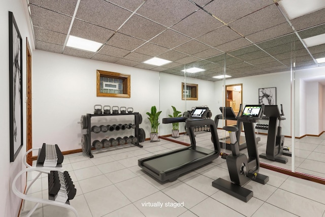 workout area with a paneled ceiling and tile patterned floors