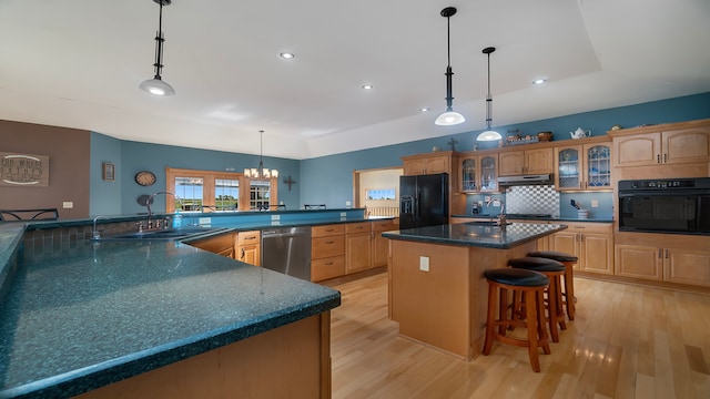 kitchen featuring sink, light wood-type flooring, a spacious island, and black appliances