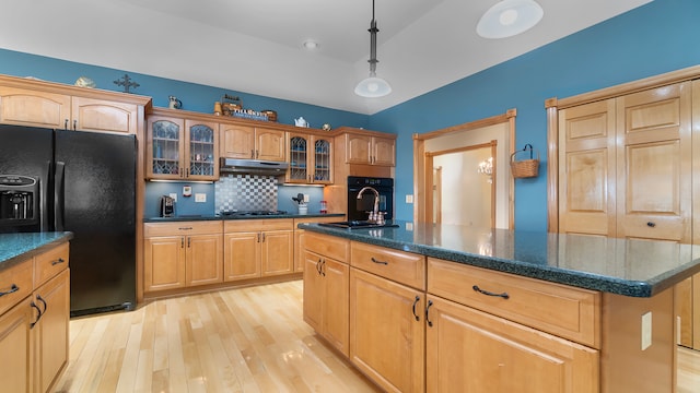 kitchen with light hardwood / wood-style flooring, pendant lighting, an island with sink, tasteful backsplash, and black appliances