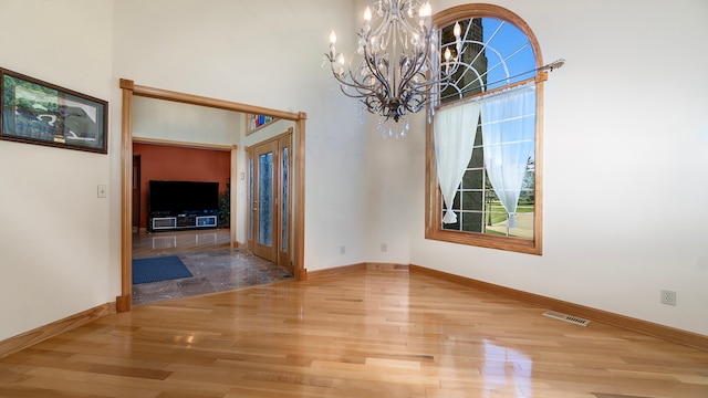 unfurnished dining area with wood-type flooring, french doors, and a notable chandelier