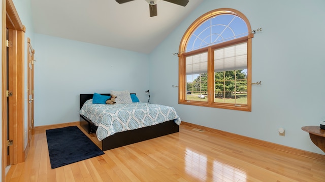 bedroom with hardwood / wood-style floors, high vaulted ceiling, and ceiling fan