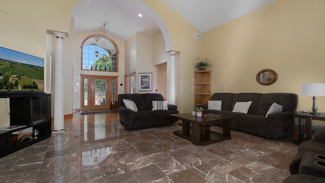 living room with decorative columns and high vaulted ceiling