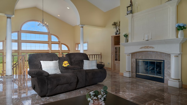 living room with high vaulted ceiling, a notable chandelier, a tiled fireplace, and decorative columns