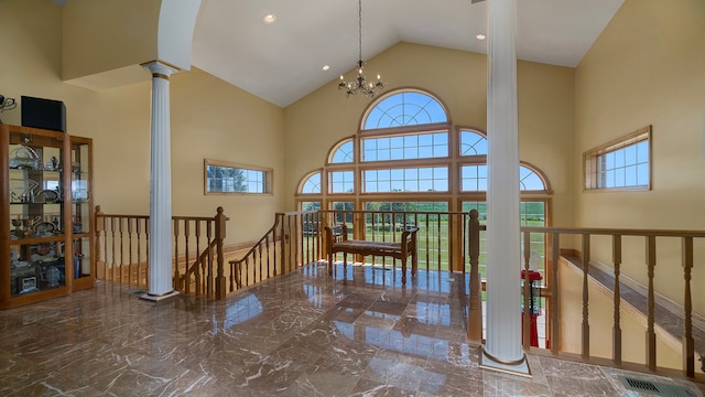 interior space featuring an inviting chandelier, high vaulted ceiling, ornate columns, and plenty of natural light