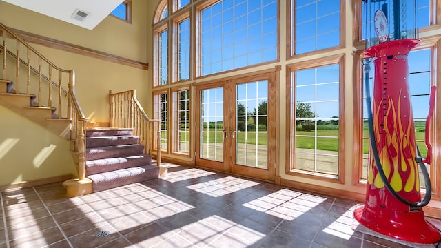 doorway to outside with french doors, dark tile patterned floors, a wealth of natural light, and a high ceiling