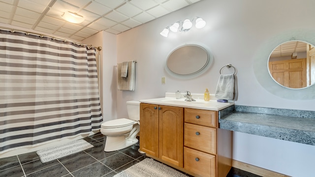 bathroom with tile patterned floors, a drop ceiling, vanity, and toilet