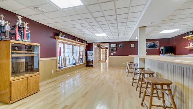 kitchen with a breakfast bar, a paneled ceiling, and light hardwood / wood-style floors