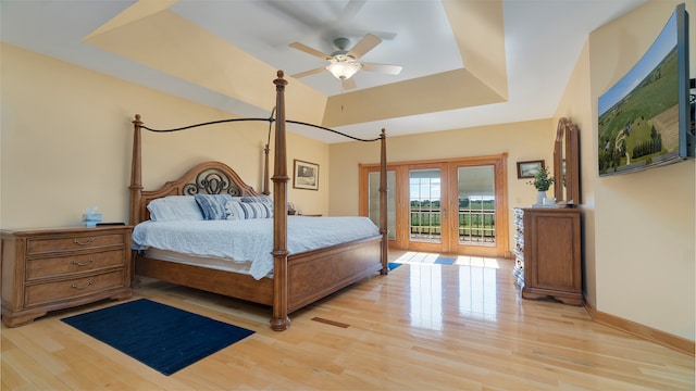 bedroom with ceiling fan, french doors, a raised ceiling, access to outside, and light wood-type flooring