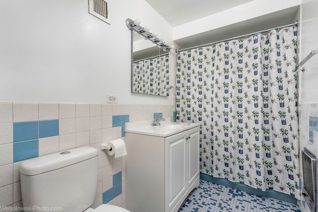 bathroom with tile patterned flooring, vanity, toilet, and tile walls