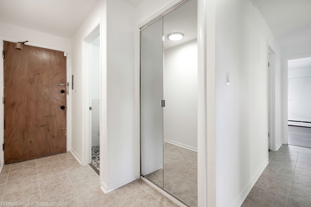 corridor featuring baseboard heating and light tile patterned flooring