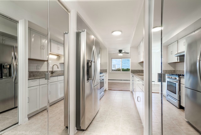 kitchen featuring backsplash, dark stone countertops, light tile patterned floors, appliances with stainless steel finishes, and white cabinetry