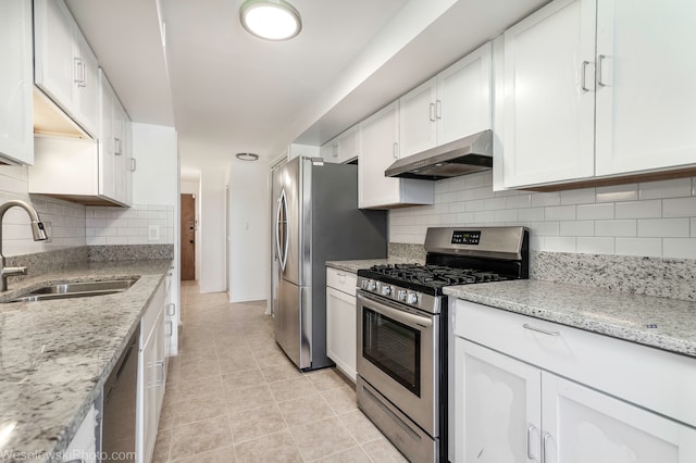 kitchen with white cabinetry, sink, stainless steel appliances, light stone counters, and backsplash