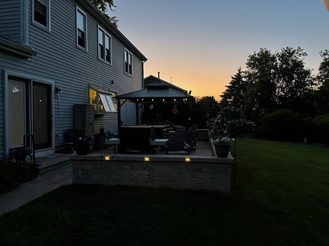 yard at dusk featuring a gazebo and a patio area