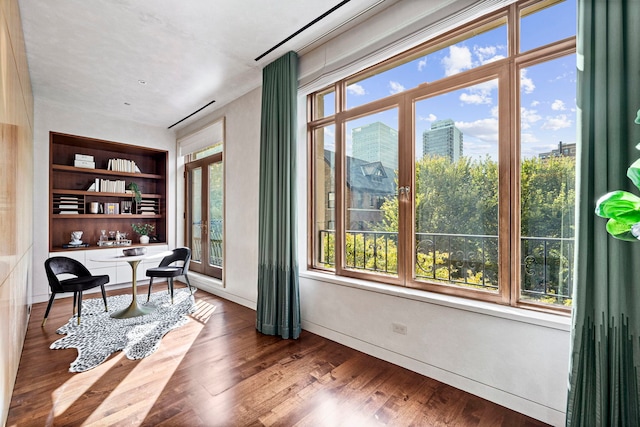 interior space featuring built in shelves, plenty of natural light, and hardwood / wood-style flooring