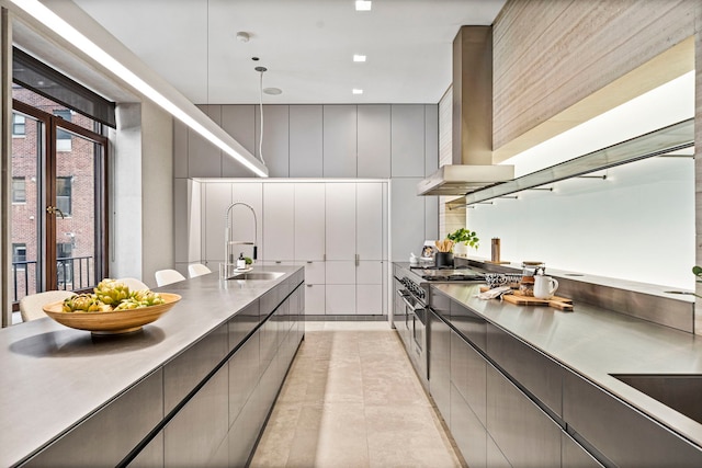 kitchen with sink, hanging light fixtures, wall chimney exhaust hood, gray cabinets, and light tile patterned floors